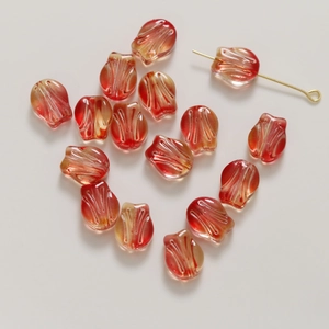 Macro detail of tulip glass beads in orange gradient for DIY jewelry making with gold pins