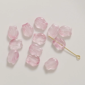 Macro shot of clear pink glass tulip flower beads with gold glitter for DIY jewelry making
