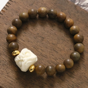 Bracciale buddista in grani di legno marrone con ciondolo creatura bianca e oro