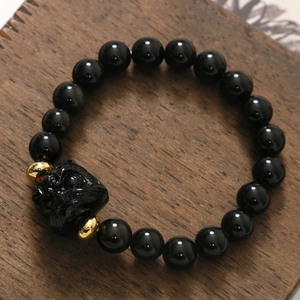 Bracciale di perle nere con ciondolo a forma di bestia intagliata e distanziali d'oro