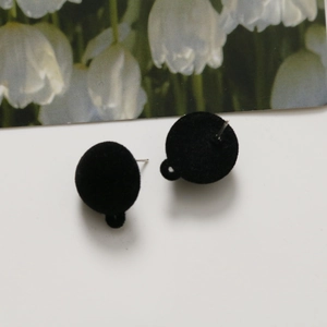 Detailed view of black flocked spherical earring charms with silver pins and hanging loops