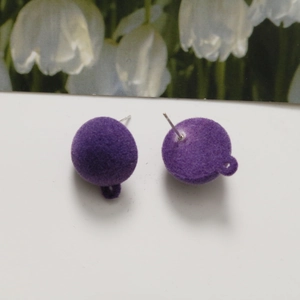 Detailed macro view of purple flocked ball earrings with functional metal hanging loops