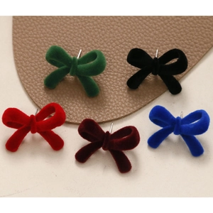 Close-up of assorted flocked velvet bow earrings in vintage dark green, red and blue