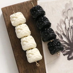 Dettaglio delle perle testa di leone bianco e nero con rilievo 3D per gioielli DIY
