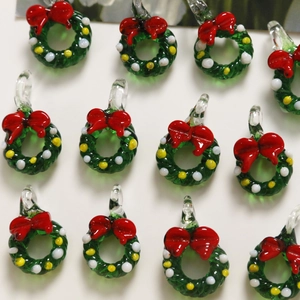 Macro view of green glass Christmas wreath pendants with red bows for jewelry DIY