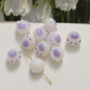 Dettaglio macro di perline a zampa di gatto bianche e viola con foro verticale per bijoux