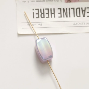Macro shot of iridescent lavender rectangular bead with golden pin on vintage background
