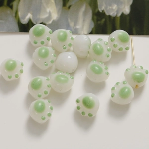 Dettaglio macro di perline in vetro 3D a zampa di gatto bianco e verde per gioielli