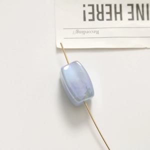 Macro detail of a light blue iridescent rectangular bead with a vertical center hole