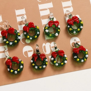 Macro detail of eight Christmas wreath glass pendants with festive red bows and beads