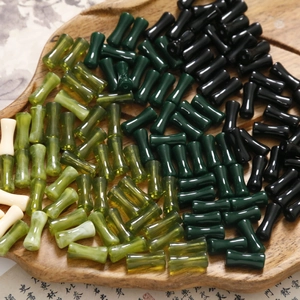 Dettaglio di perle in acrilico a forma di bambù in varie tonalità di verde su legno