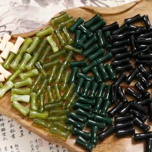 Dettaglio macro di perline in resina a forma di bambù in verde giada e nero per bijoux DIY