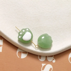 Detailed close-up of light green translucent cat paw beads for DIY jewelry making