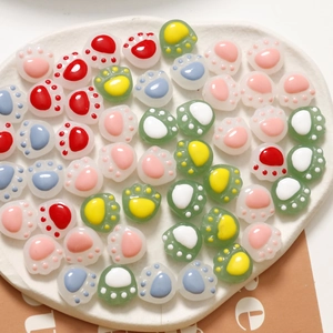 Macro shot of colorful resin cat paw charms for DIY accessories on a white heart tray
