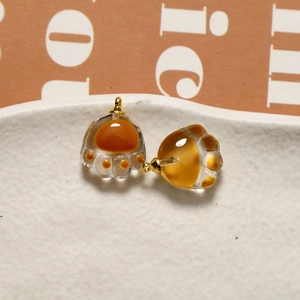Close-up of cat paw charms in glass material on white tray for DIY jewelry making