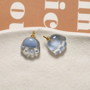 Detail of two blue cat paw glass charms with gold metal hooks for DIY jewelry making