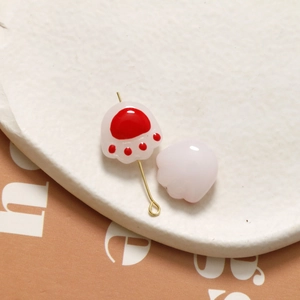 Detailed close-up of cute 3D cat paw glass beads for DIY jewelry with gold pin hardware