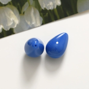 Dettaglio di perline in resina a goccia blu scuro con foro e finitura lucida a specchio