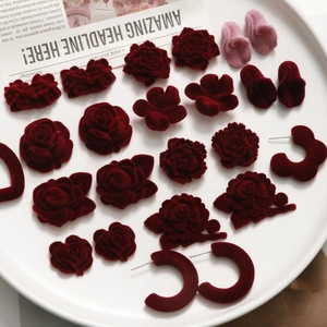 French vintage deep red velvet rose and daisy flower earring components on a ceramic plate