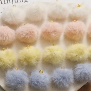 Dettaglio di ciondoli a pompon morbidi con anelli in metallo dorato in colori pastello
