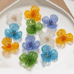 Macro view of colorful beaded flower accessories in white tray for DIY crafts