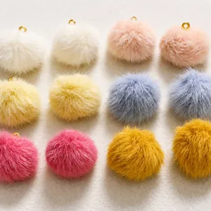 Dettaglio di pompon di peluche colorati con anelli in metallo dorato per gioielli fai-da-te