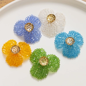 Handcrafted beaded crystal flower charms in five colors on a white ceramic plate