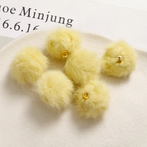 Dettaglio di pompon in peluche giallo chiaro con ganci dorati per orecchini fai-da-te