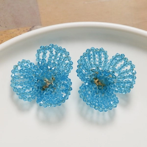 Detailed macro view of handmade light blue crystal beaded flower earrings on white plate
