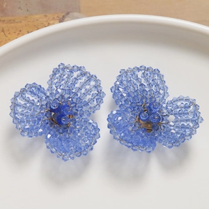 Detailed close-up of handmade blue crystal beaded flower earrings on white ceramic plate