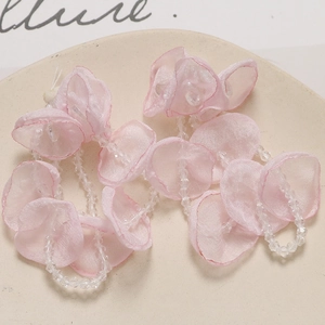 Detailed view of handmade pink silk flower petals with transparent crystal beads on ceramic