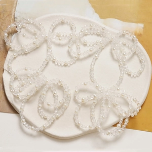 Elegant white pearl and faceted crystal bead layered jewelry on a ceramic tray