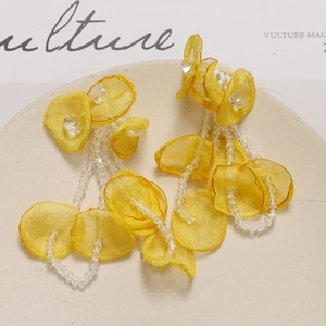 Detail of yellow tulle petal earrings with crystal tassels on a ceramic tray