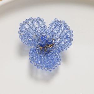 Macro detail of a handmade blue crystal beaded flower accessory with gold core