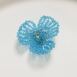 Macro detail of a handmade blue crystal flower ornament with gold wire weaving