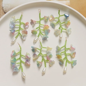 Gros plan de six pendentifs fleurs de muguet faits à la main dans une assiette en céramique