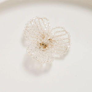 Macro detail of handmade beaded flower accessory with faceted clear crystals and gold wire