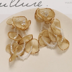 Macro view of long champagne gold organza flower petals and crystal bead tassel details