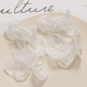 Detailed macro view of long white tulle flower earrings with crystal tassel accents