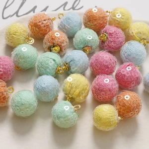 Close-up of colorful plush sequin balls with gold metal loops for DIY jewelry making