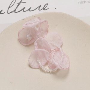 Close-up of handmade pink fabric flower petals with crystal beads on a ceramic plate