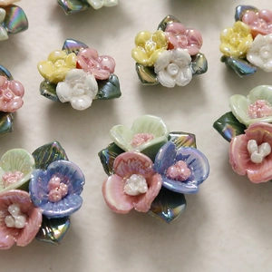 Macro-opname van kleurrijke keramische bloemkralen met iriserende afwerking en metalen blad