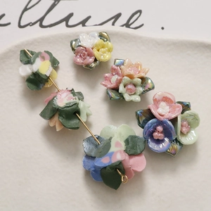 Gekleurde keramische rozen en bladkralen voor DIY-sieraden op een wit keramisch dienblad