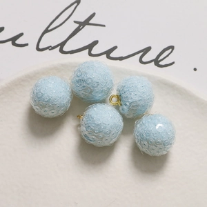 Macro detail of light blue sequin balls with gold metal loops for DIY jewelry making
