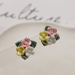 Detail van keramische bloemenoorknopjes met roze gele en witte rozen en groene bladeren