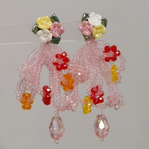 Detail van gebloemde kwastjes oorbellen met harsrozen en druppelvormige kristallen hanger