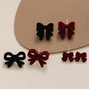 Vue détaillée de clous d'oreilles nœuds en velours noir et bordeaux sur un support cuir