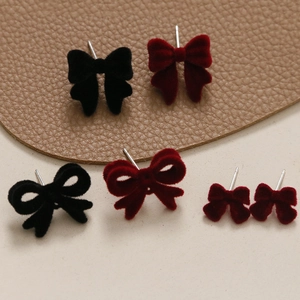 Gros plan sur des boucles d'oreilles nœuds en velours noir et rouge vin avec clous en argent