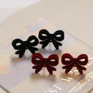 Vue détaillée de boucles d'oreilles nœuds en velours rouge et noir sur carte de luxe