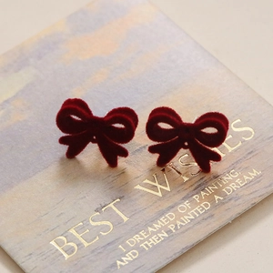 Détail des boucles d'oreilles nœud rouge avec texture velours et tiges en argent S925